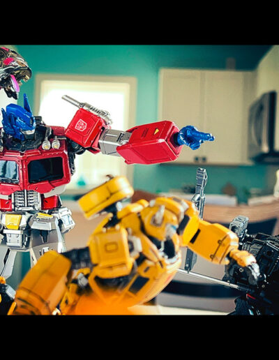 Optimus Prime, Griswing, Bumblebee, and the Diaclone Gamma Versaulter run towards the right in this toy photo